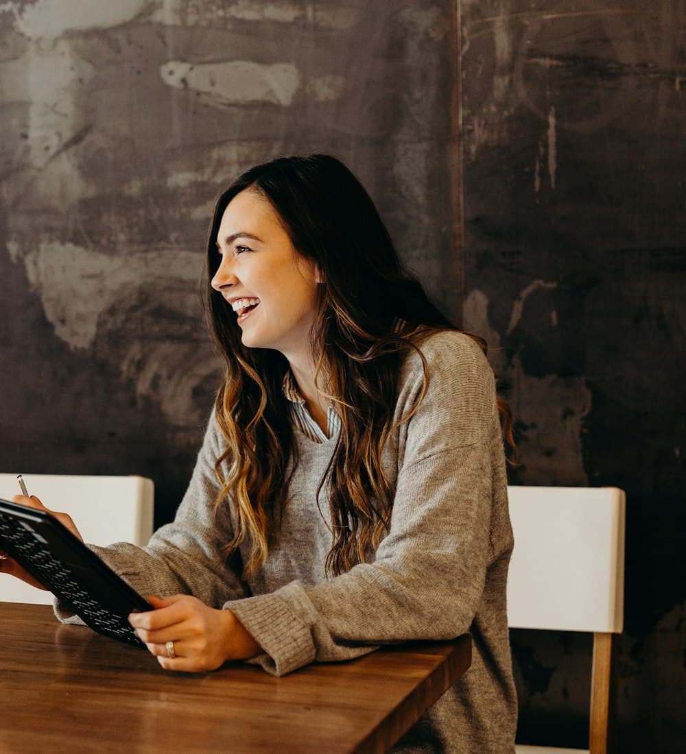 A smiling tutor preparing a lesson on a tablet