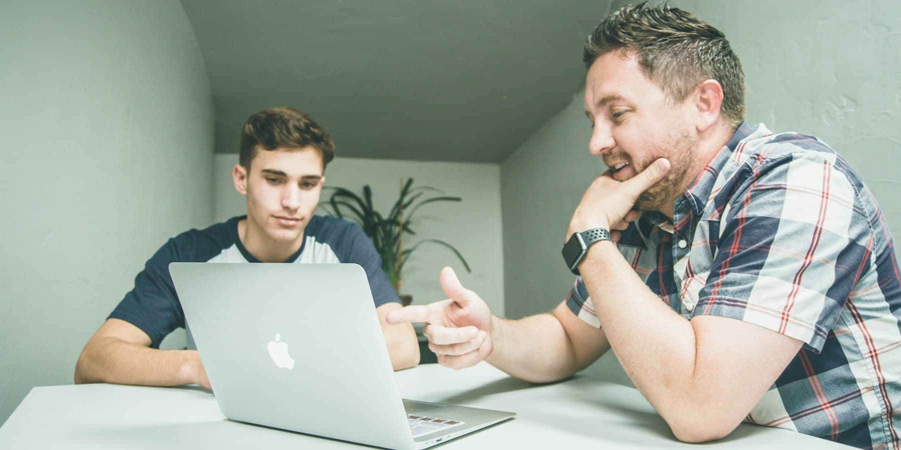 A tutor reviewing work on a laptop with a secondary student